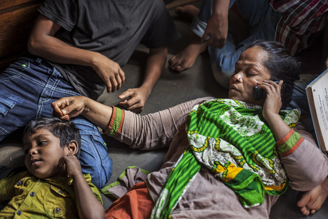 Shahidul Alam, A busy woman, Hajera is on the phone arranging supplies for her orphanage, while removing lice from the hair of one of the kids, 2014. From the series: Still She Smiles, 2014 © Shahidul Alam/Drik/Majority World